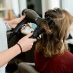 woman in red long sleeve shirt holding hair blower