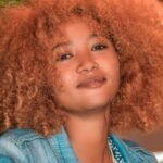 a woman with red curly hair is smiling