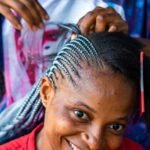 a woman smiling while getting her hair cut
