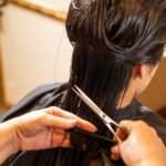 a woman cutting another woman's hair with scissors